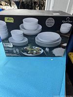 Photo of boxed 30-piece dinnerware set by Maison Neuve on blue surface, showing set contents.