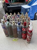 Lot of 32 Bath & Body Works home spray fragrance bottles arranged in rows on a table, showing various spray nozzle colors and worn labels, some bottles with residue from leaks.