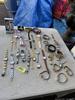 Full view of all 23 ladies watches laid on table showing various styles and bands.