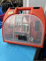 Closed red-orange carrying case with transparent plastic compartment showing organized drill bits and accessories. Black & Decker branding visible on front.