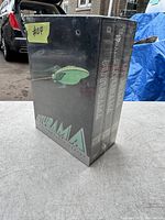 Front and side view of the Futurama complete series DVD box set still shrink-wrapped, showing the spaceship artwork and series title.