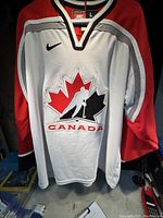 Front view of Hockey Canada hockey jersey hanging on hanger showing large embroidered logo and Nike swoosh on chest.
