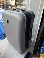 Side view of silver textured hard shell suitcase showing overall condition