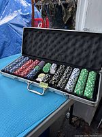 Open aluminum case displaying stacks of poker chips of various colors arranged in rows inside foam-lined compartments.