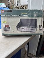 Front view of the box showing Ozark Trail Propane Camping Stove with descriptions and branding.