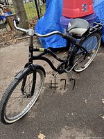 Side angled photo showing front half of the black retro step-through bicycle with white-wall tires, curved frame, and front fender.