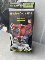 Photo of the Fusion Shoulder Dolly Mini box showing product name, branding, and lifting demonstration graphics.