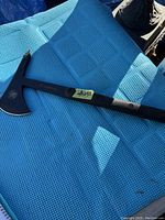 Full view of the Smith & Wesson Extraction Axe laid on a blue textured surface, showcasing the 16 inch length and full axe design.
