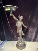 Full front view of bronze cupid statue holding platform