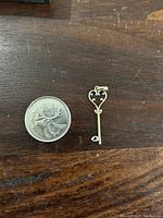 Pendant next to a 25 cent Canadian coin showing relative size of small key pendant.