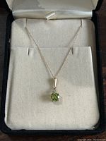 Full view of the 14k gold necklace displayed in a jewelry box with the peridot pendant centered.