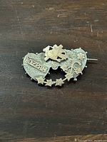 Front side of antique brooch showing sterling silver and rose gold combination with detailed heart designs and stars