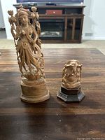 Photo showing front view of the two wood carvings on a wooden table in a living room setting.