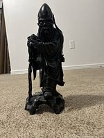 Front view of the carved wise man figure, showing details of the face, hat, robe, and staff.