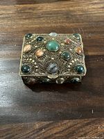 Top view of gilt metal rectangular box showing gemstones and filigree detail
