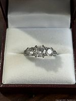 Front view of sterling silver ring with three clear stones in a white cushioned case.