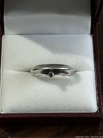 Front view of the sterling silver ring with small purple stone in center, displayed inside a cushioned ring box.