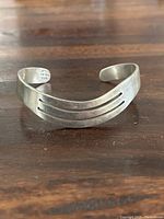 Front view of sterling silver cuff bangle showing double cutout lines on top surface