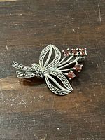 Front view of sterling silver floral brooch with garnet stones on wooden surface