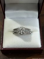 Front view of sterling silver ring with large clear round stone in center and smaller stones along band.