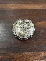 Top view of the small sterling silver container showing tarnish and floral crown engraving.