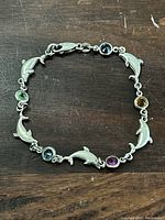 Top view of the sterling silver dolphin and gemstone bracelet showing the alternating dolphin shapes and colorful round gemstones.