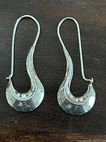 View of front-facing sterling silver earrings on dark surface