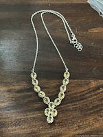 Necklace laid flat on a wooden surface showing the pendant with yellow oval stones.