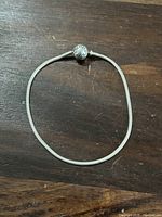 Full view of the silver snake chain Pandora bracelet laid flat on a wooden surface.