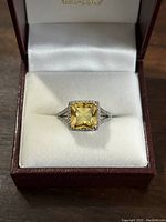 Front view of sterling silver ring with square yellow gemstone in jewelry box.