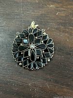Front view of the Victorian mourning pendant showing the black enamel geometric and floral design with a central pearl.