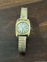Front view of the women's Bulova Accutron watch showing gold-tone case, silver dial with gold markers, and expandable metal band.