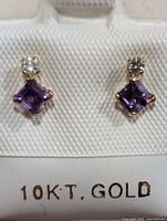 Pair of 10K gold earrings with square-cut purple amethyst and small round diamonds, displayed on white background with 10K gold mark visible.