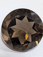 Close-up front view of round faceted smokey quartz gemstone showing star-shaped interior reflections and brown smoky coloring.