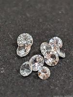 Photo showing a group of round-cut white sapphire gemstones on a dark background, highlighting their transparency and cut.