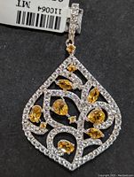 Close-up of the silver teardrop-shaped pendant with citrine and cubic zirconia stones, showing intricate openwork design.