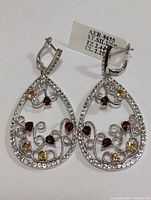 Front and side view of the pair of sterling silver teardrop shaped earrings with citrine, garnet and cubic zirconia stones on a white background. One photo shows both earrings upright and the second photo shows them lying flat.