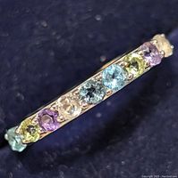 Close-up photo showing top view of silver ring set with various colored gemstones arranged in a line.