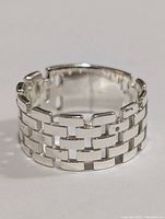 Front view of silver ring showing brick link pattern design and open adjustable back.