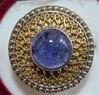 Close up top view of round tanzanite cabochon set in ornate silver filigree ring