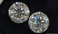 Close-up of two round cut moissanite gemstones with visible facets and brilliance.