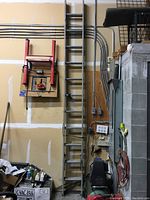 Full view of the aluminum extension ladder in storage against a wall, showing the ladder in its extended state.