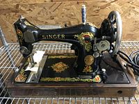 Black Singer sewing machine on wood base with decals, handwheel, spool stand and power cord