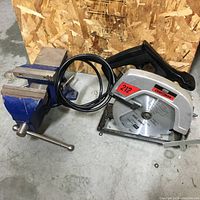 Photo showing the blue swivel bench vise and the Craftsman skill saw side by side on the floor.