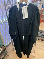 Full front view of black barristers robe hung on a hanger with white bib collar visible.