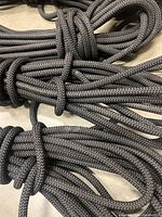 Close-up photo of thick braided black rope coiled and tied, showing texture and color.