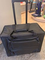 Closed view of the Janome rolling case showing telescopic handle extended and front zipper pocket.