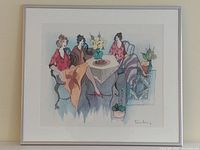 Photo showing the full framed artwork of three ladies seated around a table with a potted plant and flowers, metal frame visible. White matting under glass.