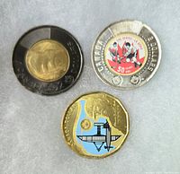 Three 2022 Canadian coins lying flat: a black ring toonie, a hockey themed colourized toonie, and a blue coloured loonie. All coins appear lightly circulated with vivid color highlights.