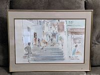 Full view of the framed watercolour painting showing the street scene with stairway and figures, framed with a thin gold frame and matte.